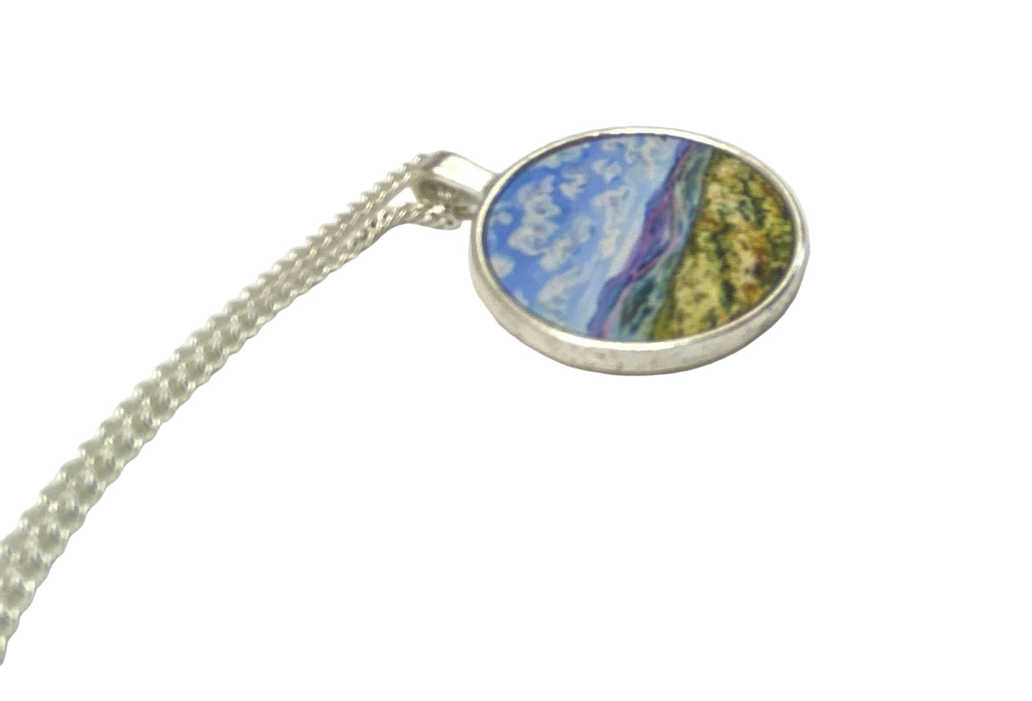Round pendant with a colorful design on a silver chain against a white background