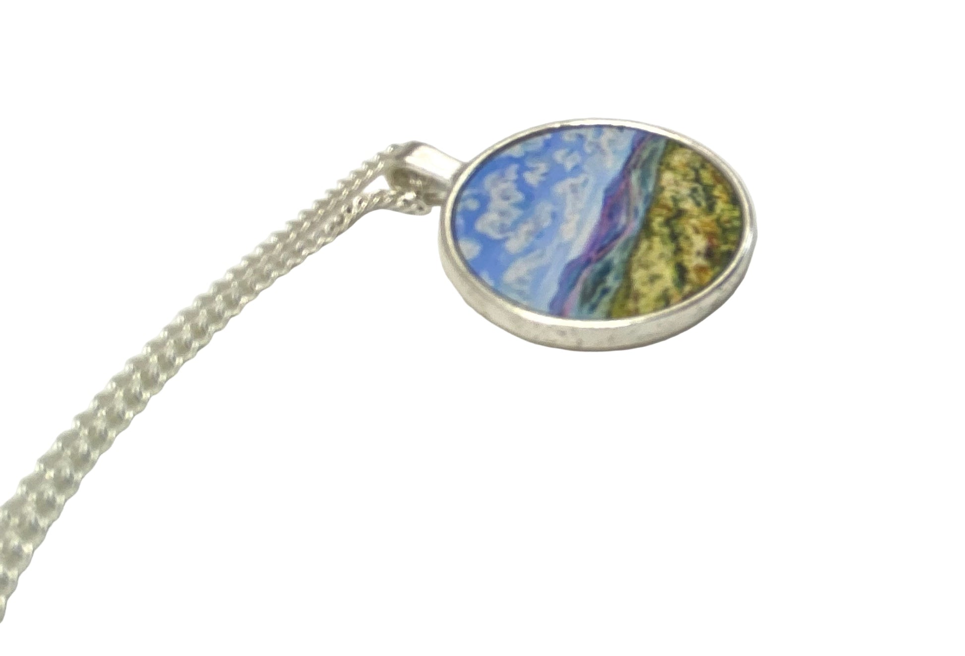 Round pendant with a colorful design on a silver chain against a white background