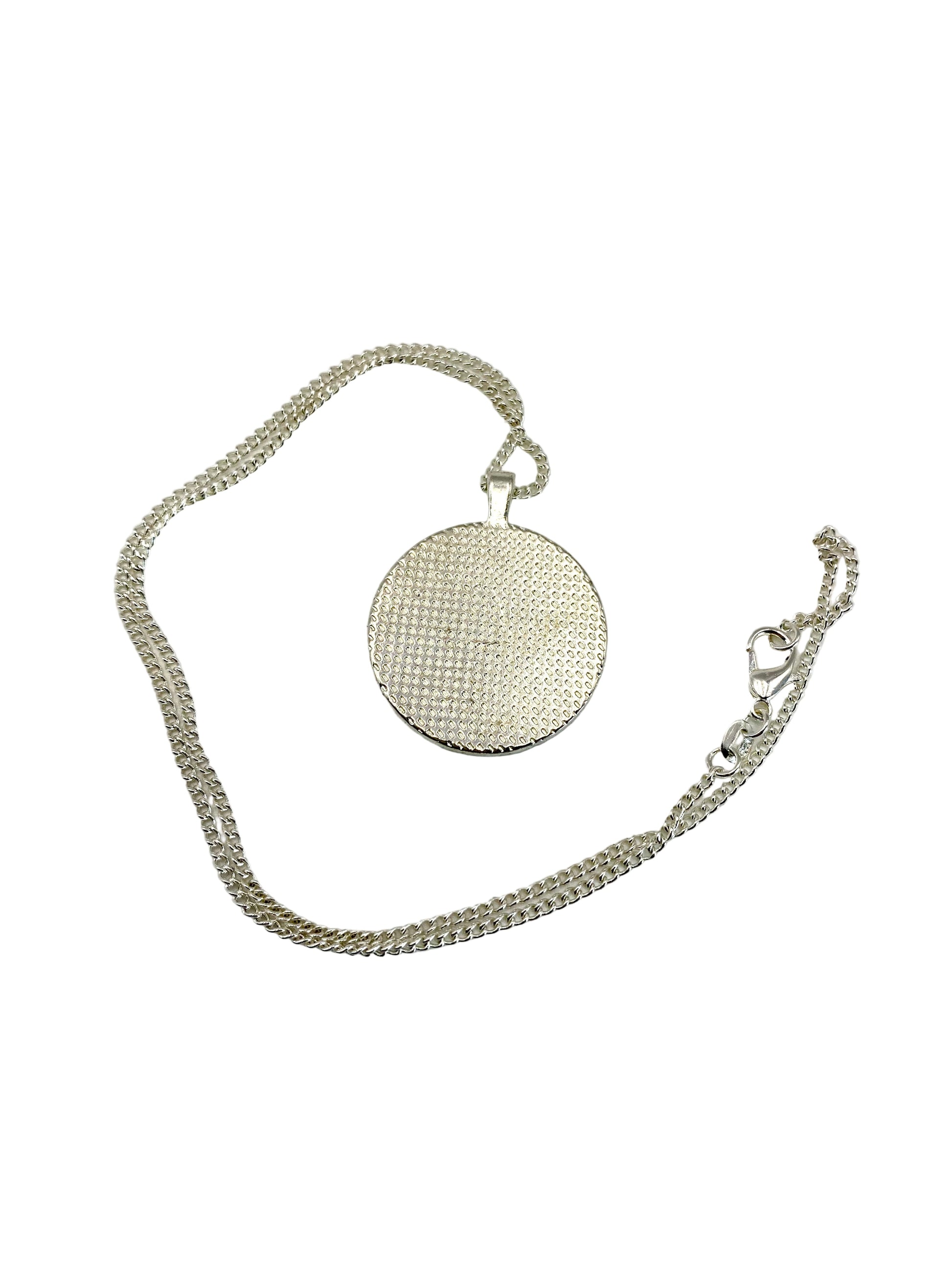 Silver necklace with a round textured pendant on a white background