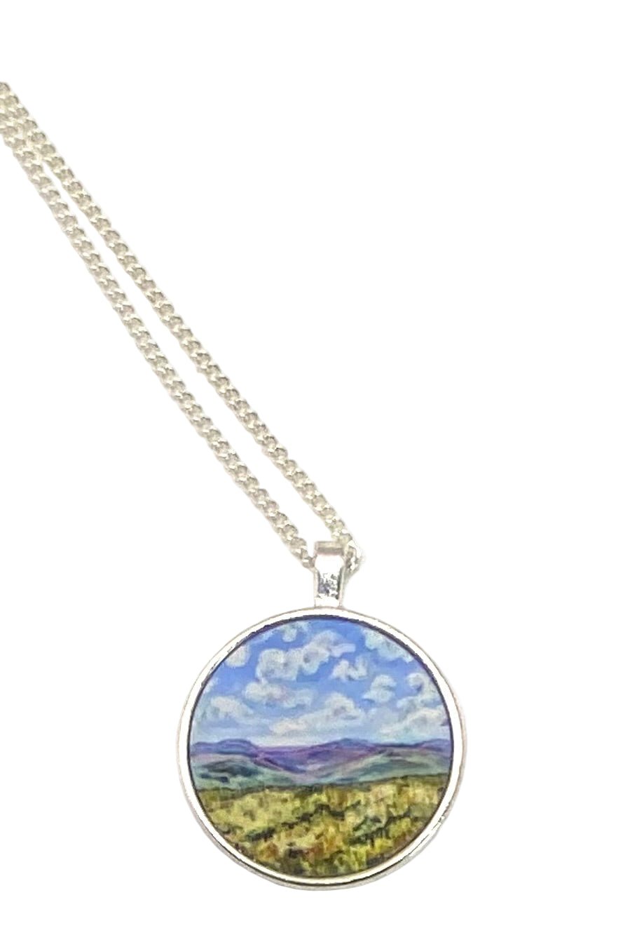 Necklace with a round pendant featuring a landscape design on a white background
