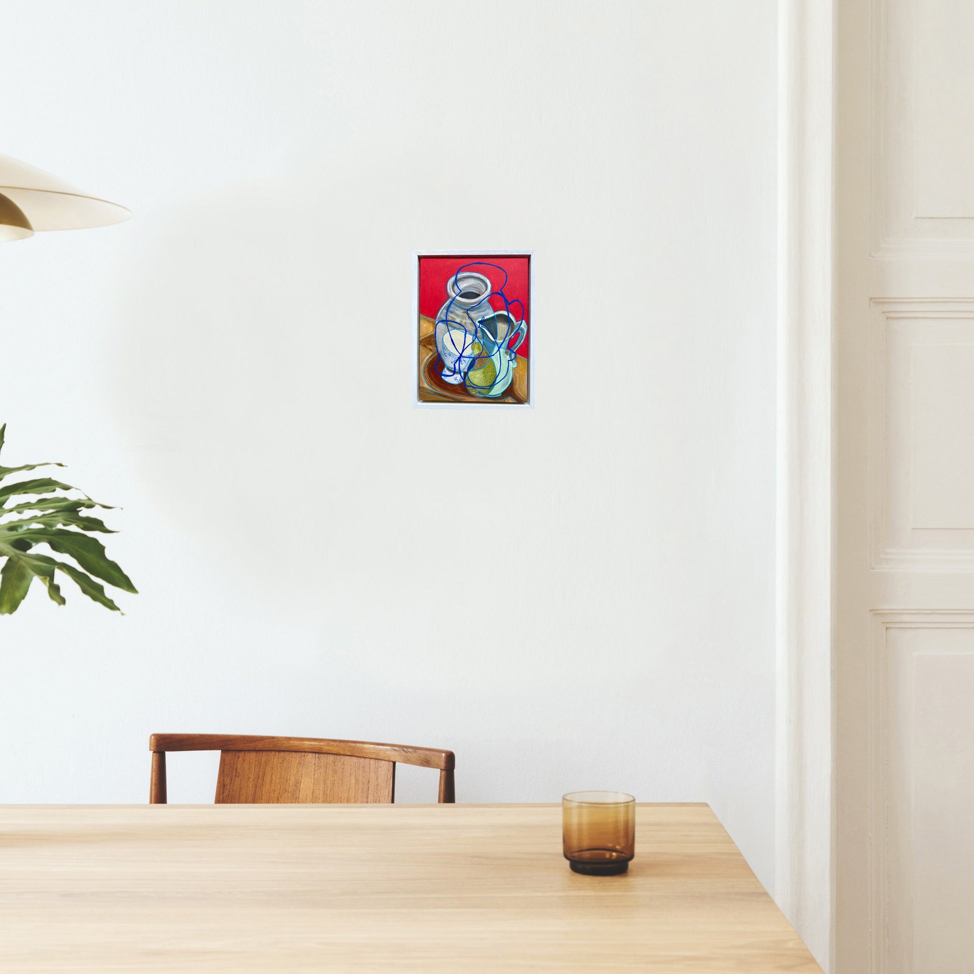 Dining room with a table, chairs, and a small still life painting on the wall by rebecca carr
